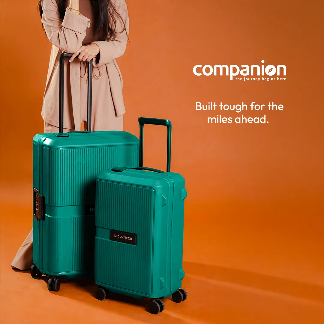 Ad: two teal hard-shell suitcases, large and small, beside a person in a beige coat, shown from the shoulders down, on orange, with the words Built tough for the miles ahead