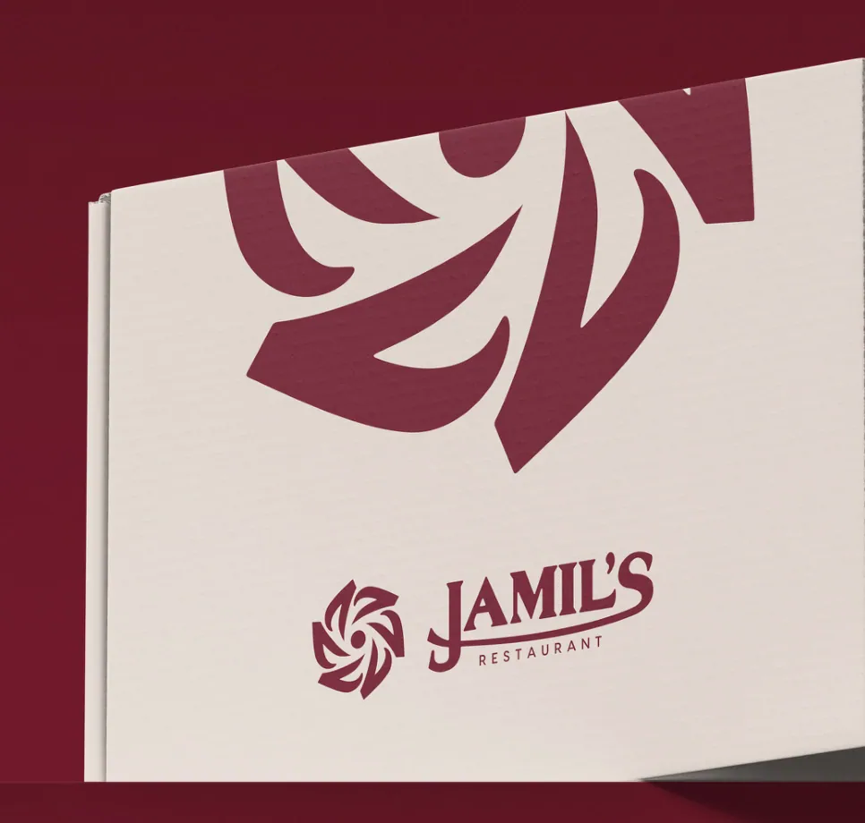 A white Jamil's barbecue box printed with a large maroon rosette, on a maroon ground