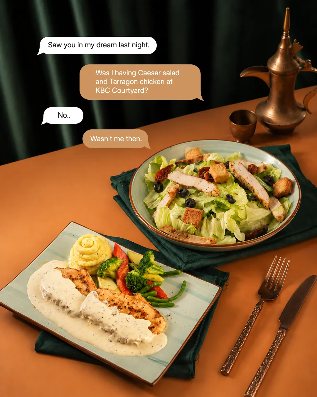 Chat bubbles about a Caesar salad and tarragon chicken at KBC Courtyard, above the two plates on an orange table