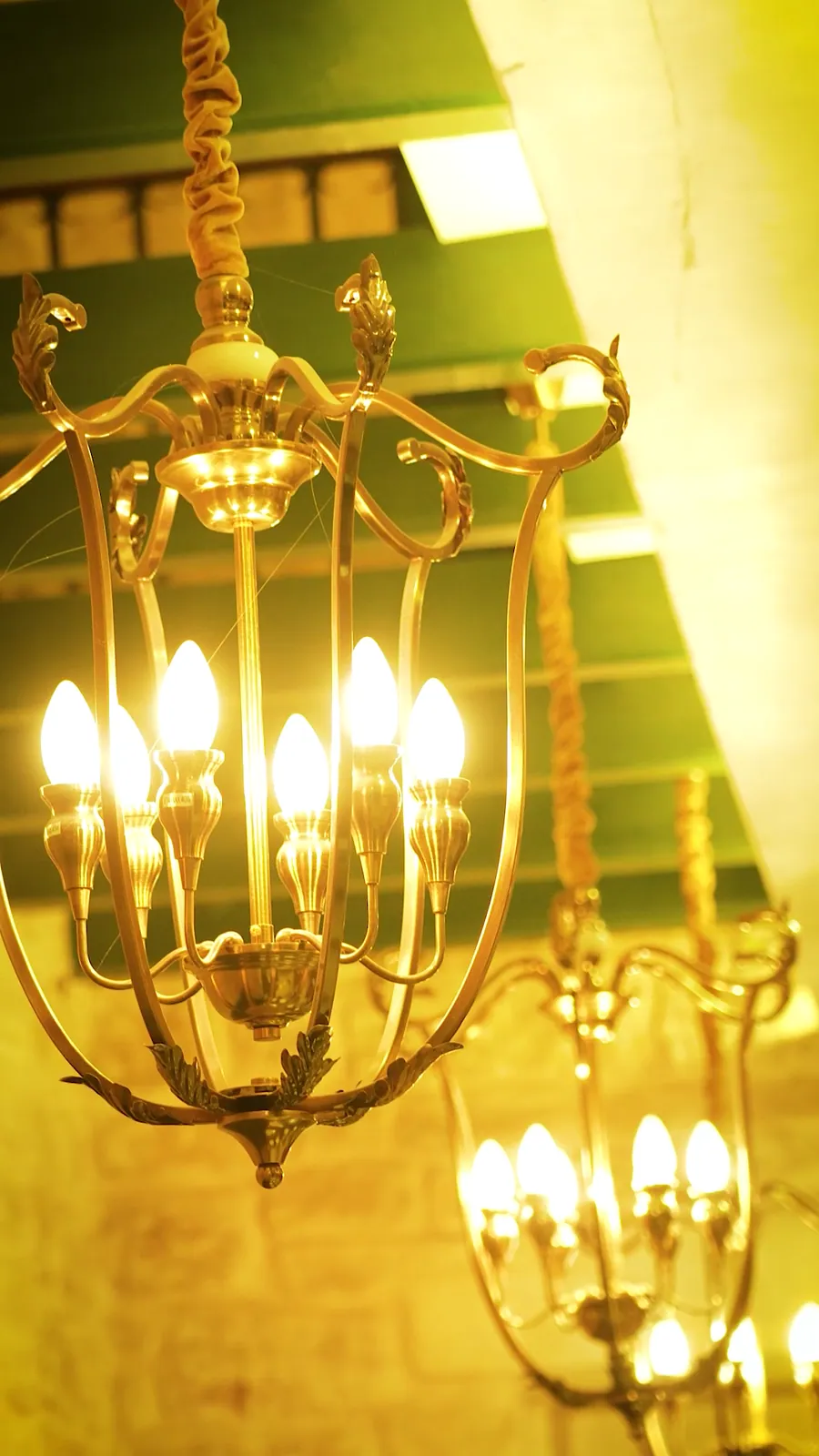 Still from a reel: brass chandeliers lit warm over the dining room