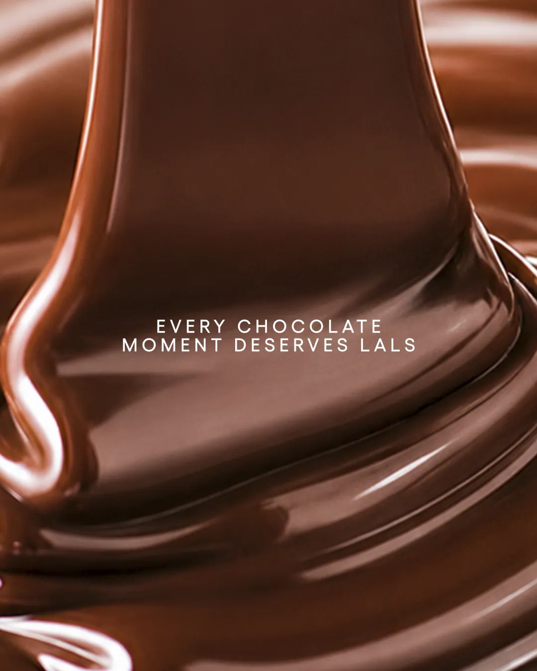 Still from a video ad: a ribbon of melted chocolate folding over itself, with the words Every chocolate moment deserves Lals